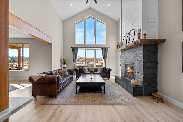 living room featuring ceiling fan, a fireplace, high vaulted ceiling, and light hardwood / wood-style floors