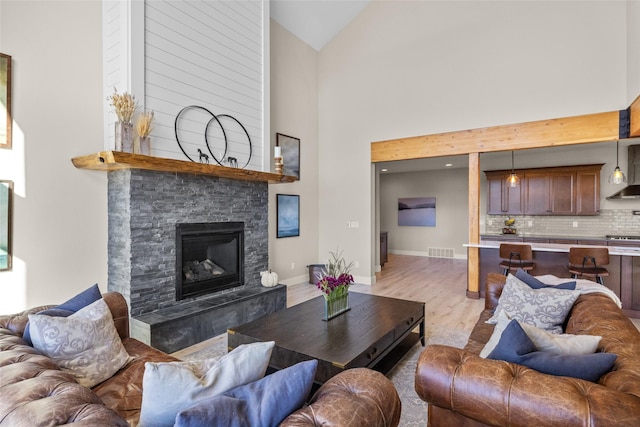 living room with a fireplace, high vaulted ceiling, and light wood-type flooring