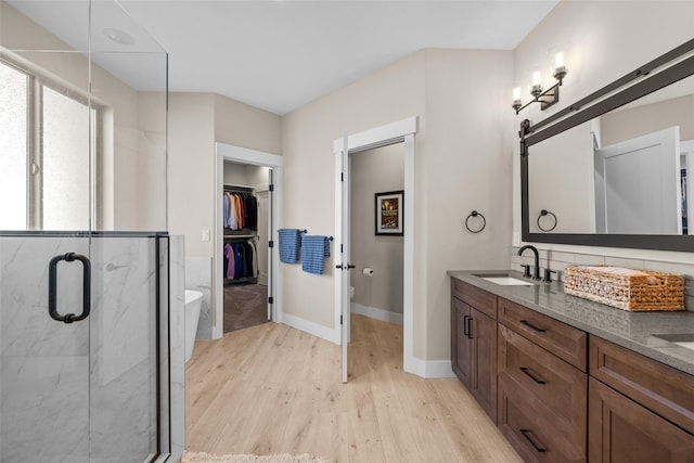 bathroom featuring wood-type flooring, vanity, toilet, and walk in shower