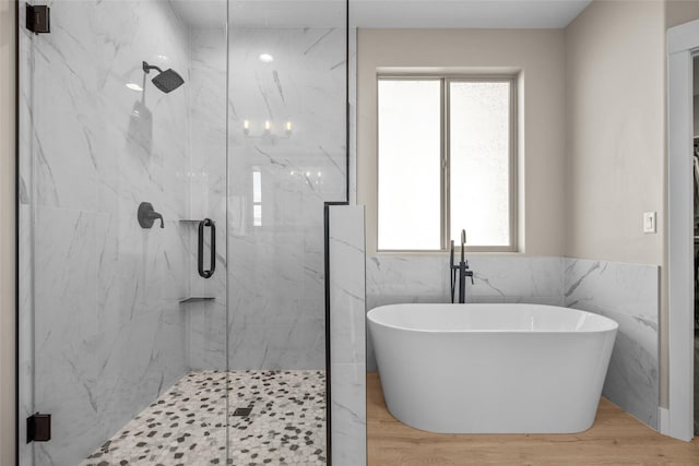 bathroom featuring hardwood / wood-style floors, plus walk in shower, and tile walls