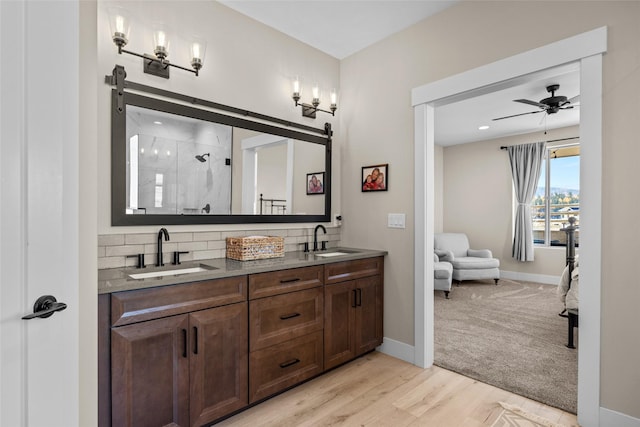 bathroom with vanity, hardwood / wood-style flooring, ceiling fan, tasteful backsplash, and an enclosed shower