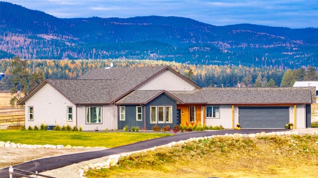 view of front of house with a mountain view, a garage, a front lawn, and cooling unit