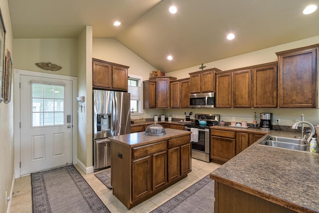 kitchen with a center island, lofted ceiling, sink, light tile patterned floors, and stainless steel appliances