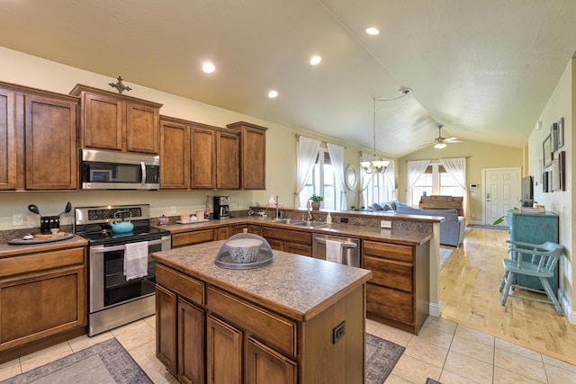 kitchen with stainless steel appliances, a kitchen island, lofted ceiling, light tile patterned floors, and ceiling fan with notable chandelier