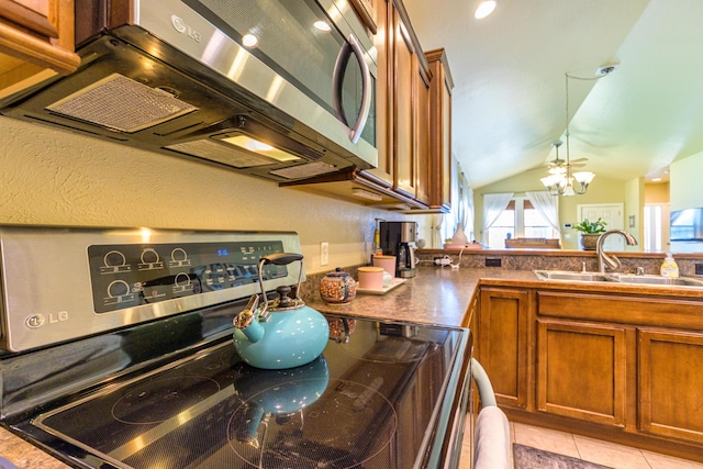 kitchen with appliances with stainless steel finishes, sink, light tile patterned floors, a chandelier, and lofted ceiling