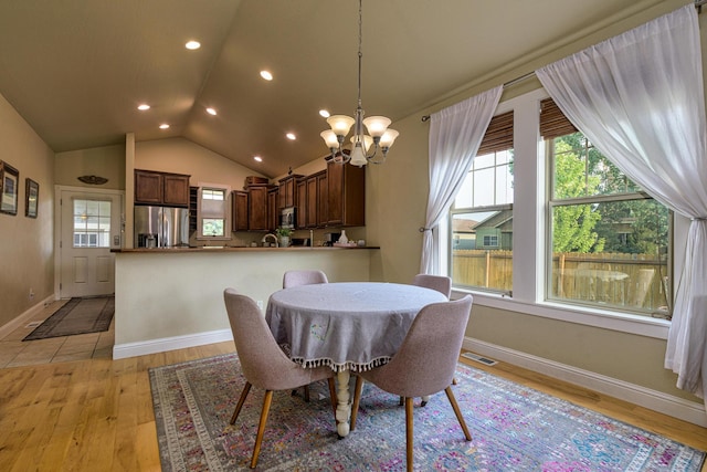 dining space featuring an inviting chandelier, lofted ceiling, a wealth of natural light, and light hardwood / wood-style flooring