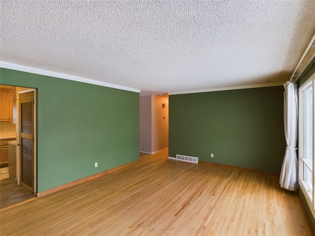 empty room with light hardwood / wood-style flooring, a textured ceiling, and ornamental molding