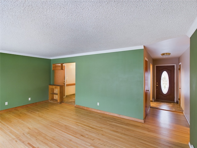 interior space with light hardwood / wood-style flooring, a textured ceiling, and ornamental molding