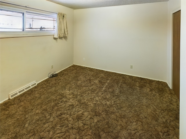 empty room with carpet floors and a textured ceiling