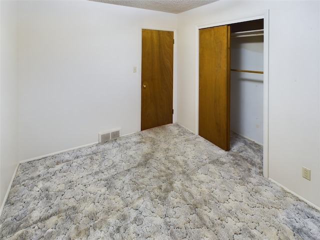 unfurnished bedroom featuring light carpet, a textured ceiling, and a closet