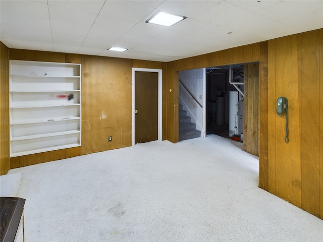 unfurnished room with built in shelves, wood walls, and carpet