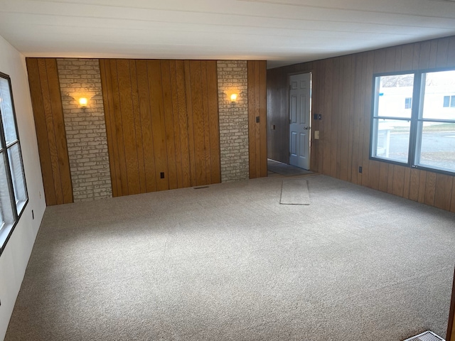 unfurnished room featuring carpet, wooden walls, and brick wall