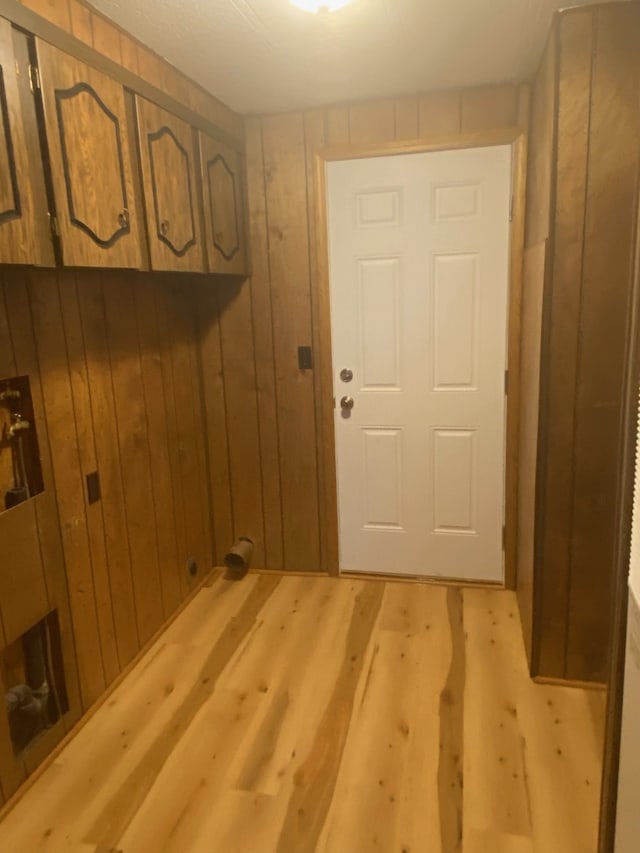 entryway with wood walls and light hardwood / wood-style flooring