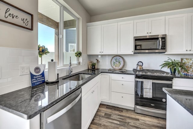 kitchen with appliances with stainless steel finishes, dark hardwood / wood-style flooring, tasteful backsplash, sink, and white cabinets