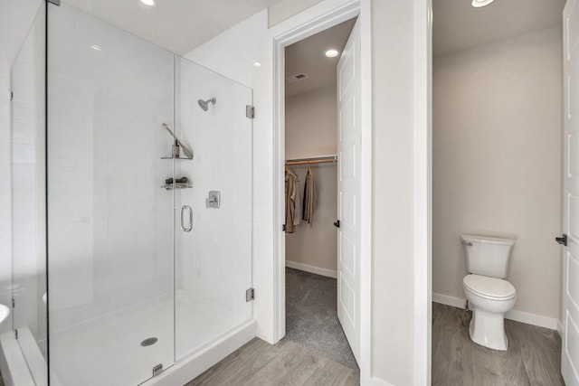 bathroom featuring wood-type flooring, toilet, and walk in shower