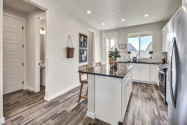 kitchen featuring dark wood-type flooring, a center island, white cabinets, and stainless steel appliances