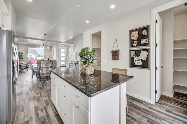 kitchen with pendant lighting, a kitchen island, white cabinetry, and stainless steel refrigerator