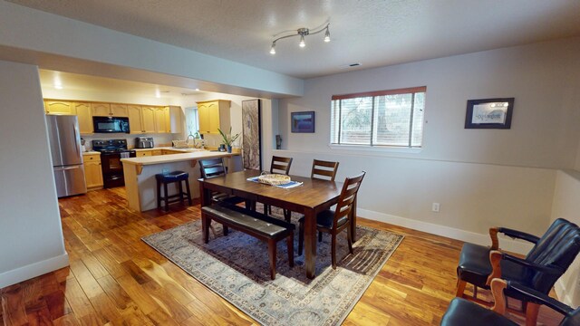 dining space with sink, a textured ceiling, and light hardwood / wood-style flooring