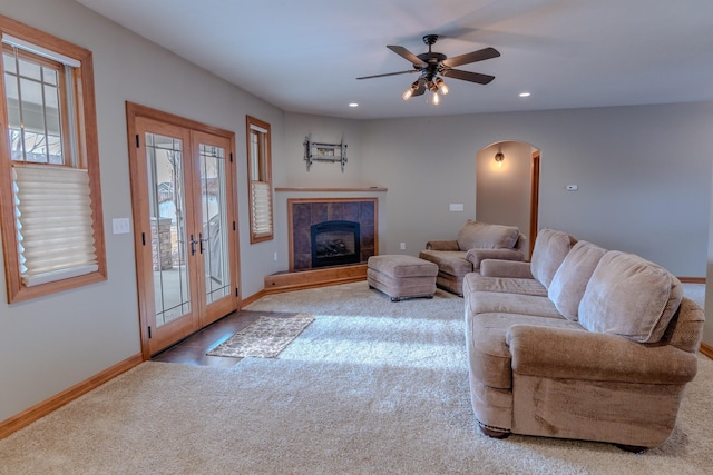 living room featuring carpet flooring, a tiled fireplace, ceiling fan, and french doors