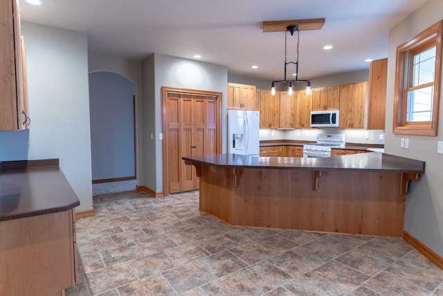 kitchen featuring kitchen peninsula, a kitchen breakfast bar, white appliances, and hanging light fixtures