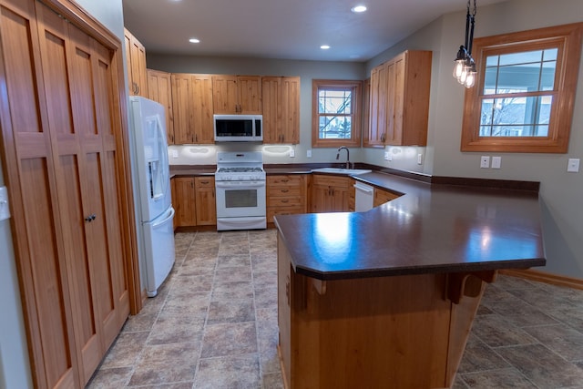 kitchen featuring a breakfast bar, white appliances, sink, hanging light fixtures, and kitchen peninsula