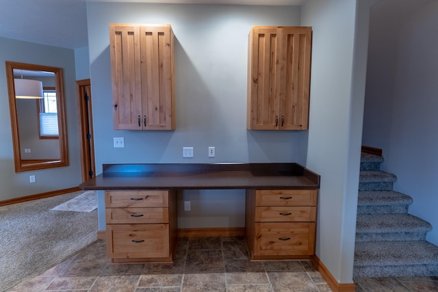 unfurnished office featuring built in desk and dark carpet