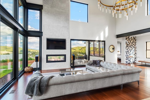 living room with hardwood / wood-style flooring, a towering ceiling, and a tiled fireplace