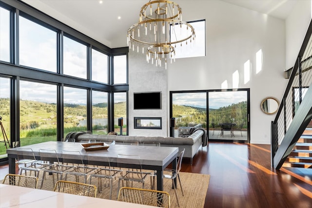 living room with a fireplace, a towering ceiling, dark hardwood / wood-style floors, and a chandelier