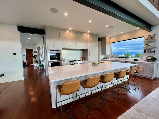 kitchen with a spacious island, light stone counters, a breakfast bar, and stainless steel double oven