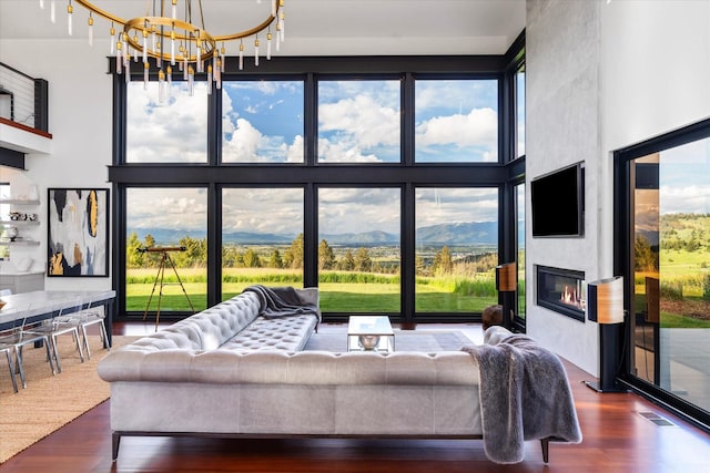 living room with a notable chandelier, dark hardwood / wood-style floors, a towering ceiling, and a fireplace