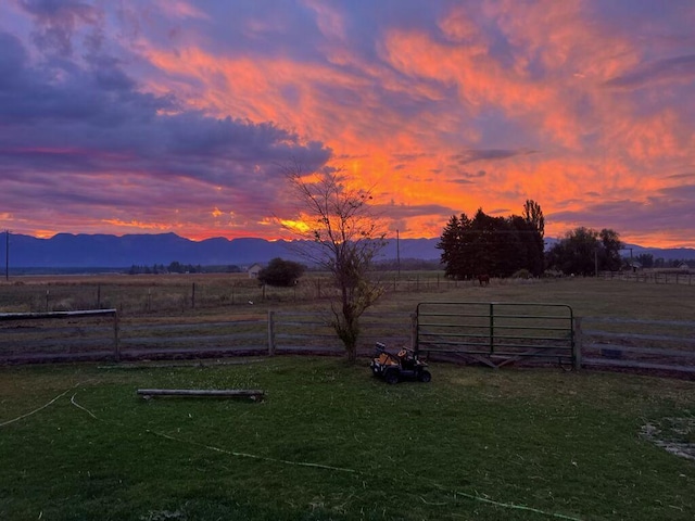 yard at dusk featuring a mountain view and a rural view