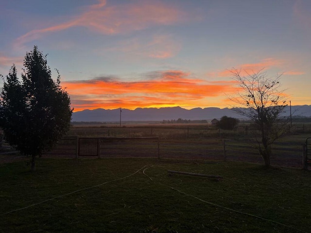 yard at dusk featuring a mountain view and a rural view