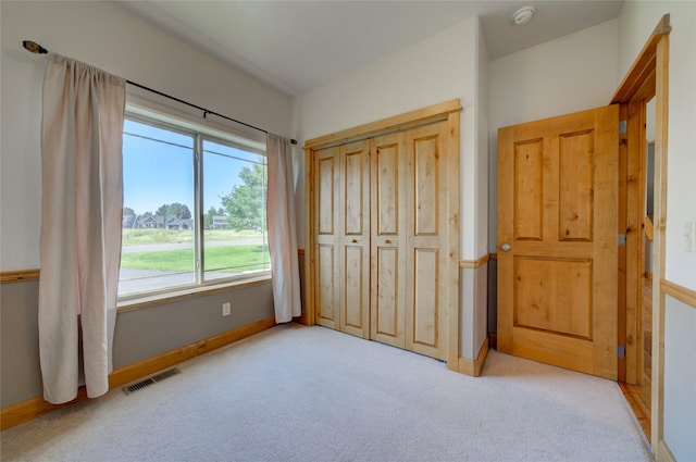 unfurnished bedroom with light colored carpet and a closet