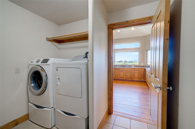 clothes washing area with washer and clothes dryer, light tile patterned flooring, and sink