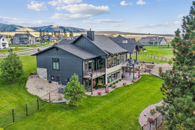 back of property featuring a lawn, a mountain view, a balcony, central AC, and a patio