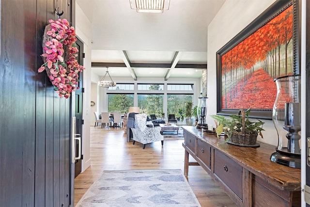 corridor with beam ceiling, light hardwood / wood-style floors, an inviting chandelier, and coffered ceiling