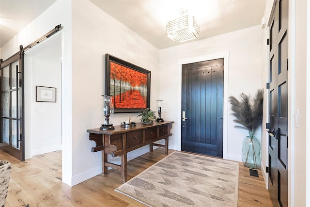 foyer entrance with a barn door and light hardwood / wood-style floors