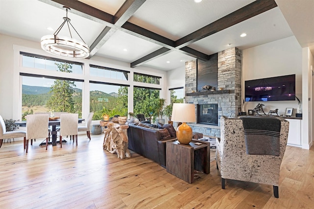 living room featuring beamed ceiling, light wood-type flooring, a fireplace, and coffered ceiling