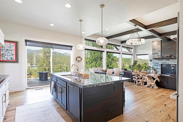 kitchen with white cabinets, sink, hanging light fixtures, light hardwood / wood-style flooring, and beam ceiling