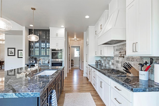 kitchen with a spacious island, custom range hood, hanging light fixtures, and appliances with stainless steel finishes