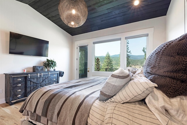 bedroom with a mountain view, light hardwood / wood-style flooring, wooden ceiling, and lofted ceiling