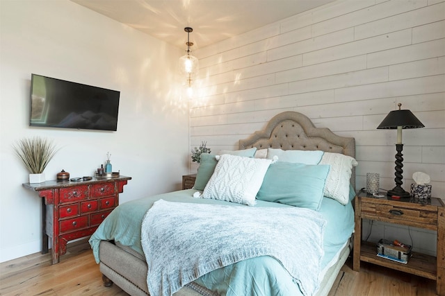 bedroom with light hardwood / wood-style flooring and wooden walls