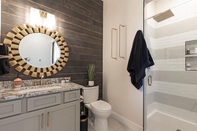 bathroom with tile patterned flooring, toilet, wooden walls, a shower with door, and vanity