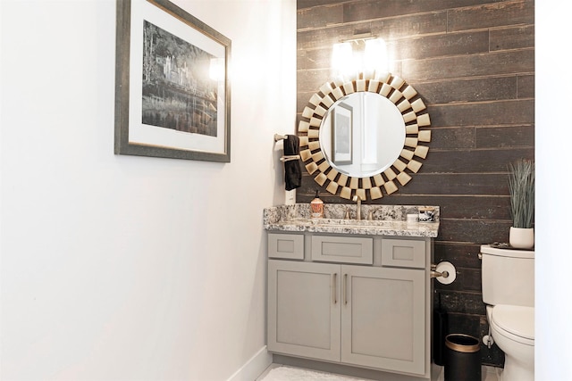 bathroom featuring vanity, toilet, and wood walls