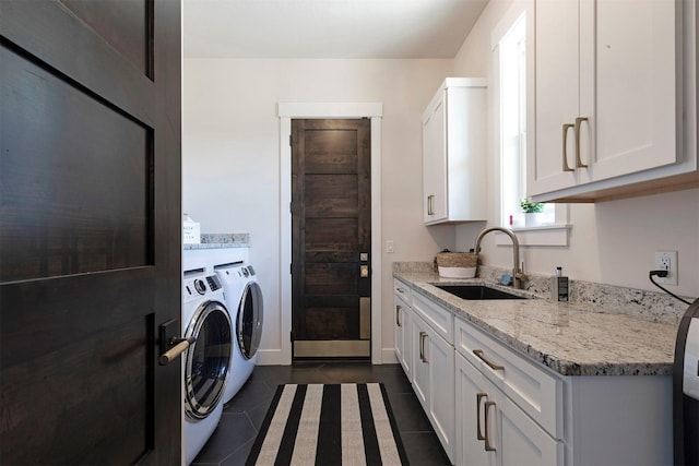 laundry area with washer and clothes dryer, sink, dark tile patterned floors, and cabinets