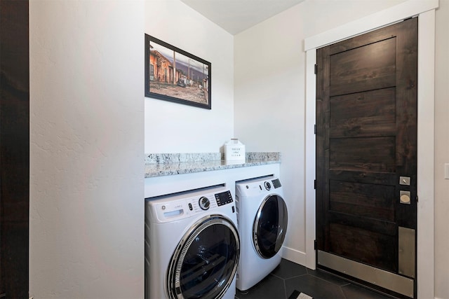 clothes washing area featuring washer and dryer and dark tile patterned floors