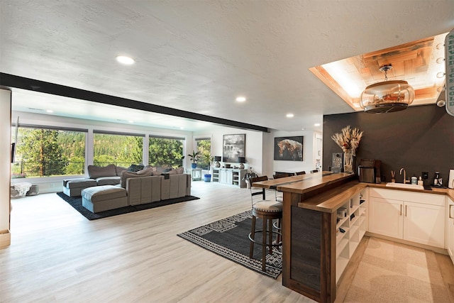 interior space with white cabinets, light hardwood / wood-style flooring, wood counters, and sink