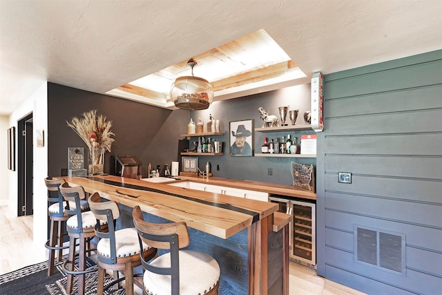 bar featuring wooden walls, wood counters, sink, and wine cooler