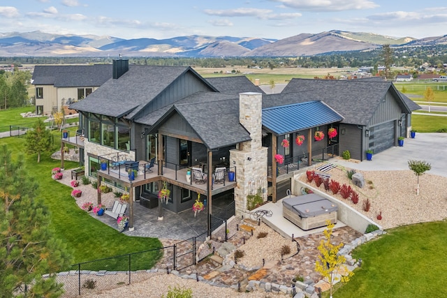 exterior space featuring a deck with mountain view, a hot tub, and a garage