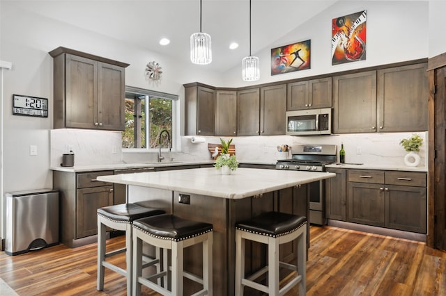 kitchen featuring tasteful backsplash, stainless steel appliances, pendant lighting, a kitchen island, and lofted ceiling